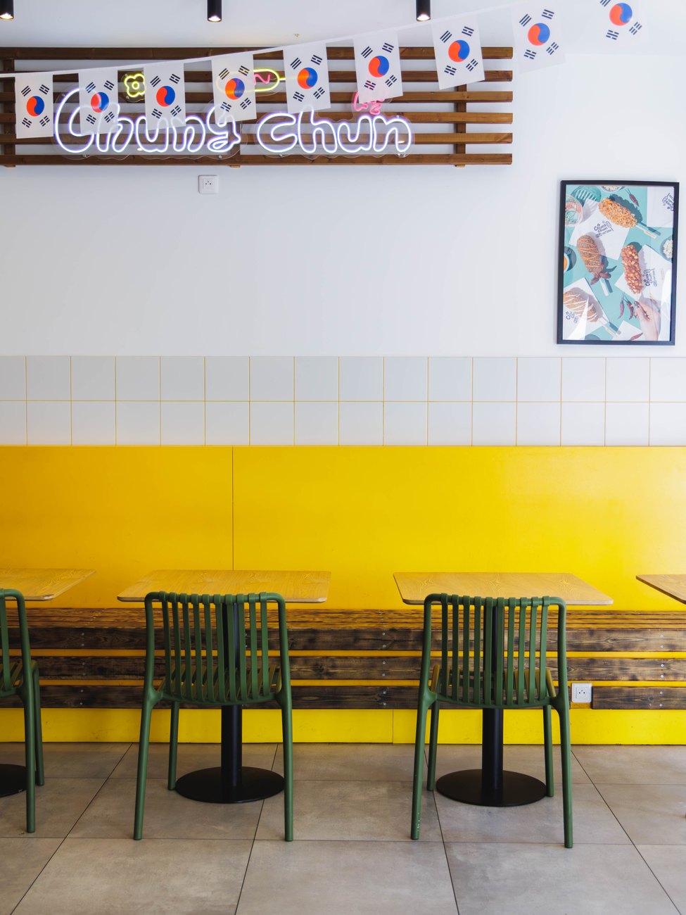 Salle du restaurant Chungchun à Nice : enseigne néon « ChungChun », guirlande de drapeaux coréens, banquettes jaunes et chaises vertes