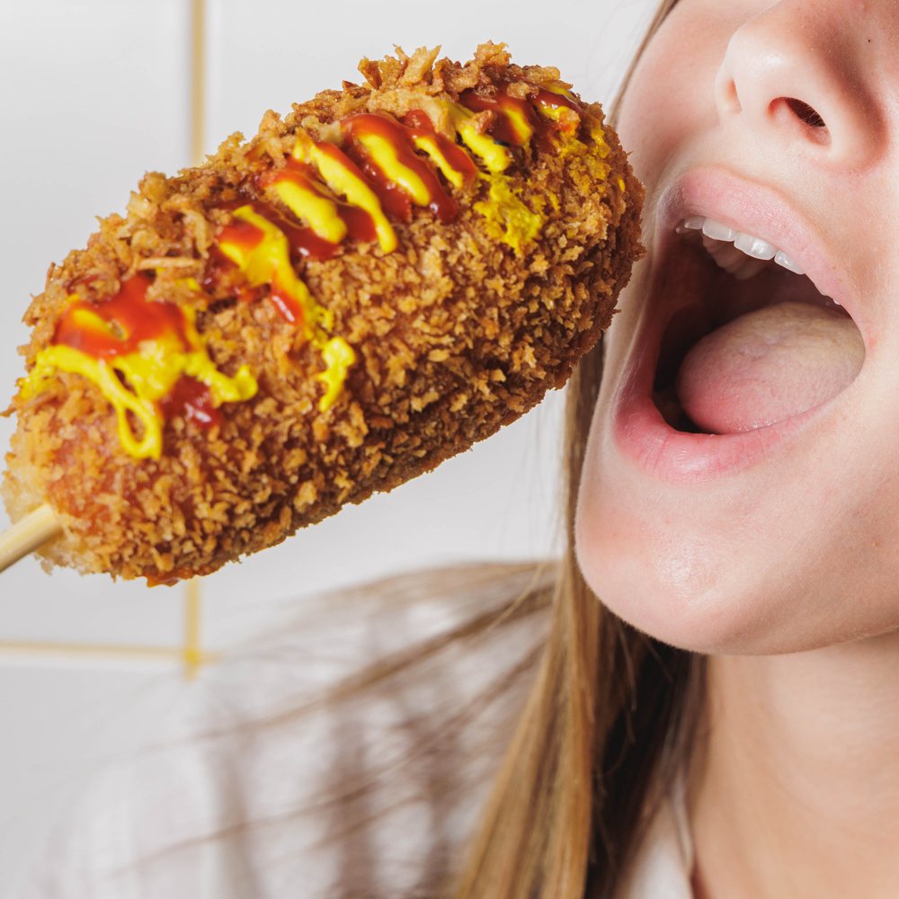Cliente croquant à pleines dents dans un Rice Dog croustillant